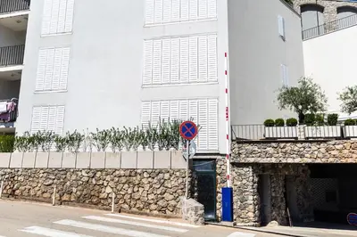 a white building with a stone wall and a street sign at Miramare Apartments Pržno in Pržno