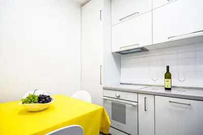 a kitchen with a yellow table with a bowl of fruit at Miramare Apartments Pržno in Pržno