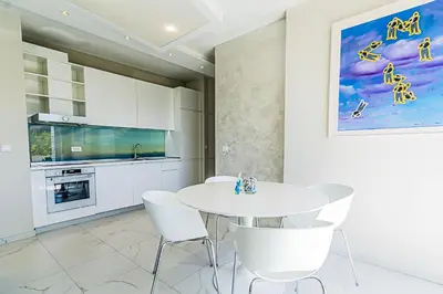 a white kitchen with a white table and chairs at Miramare Apartments Pržno in Pržno