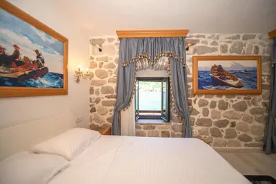 a bedroom with a bed and a stone wall at SEASIDE HOUSE KOTOR in Kotor