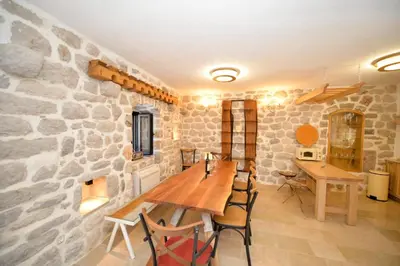 a dining room with a stone wall and a wooden table at SEASIDE HOUSE KOTOR in Kotor