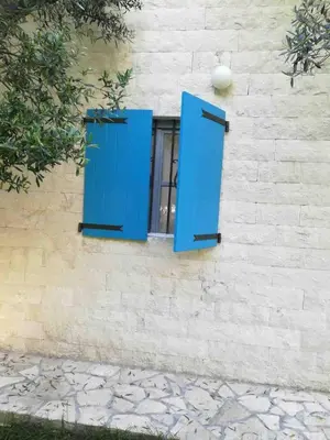 a window with blue shutters on a building at Rajana Bungalow 2olive House in Ulcinj
