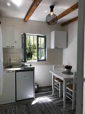 a kitchen with a white table and a white table and a window at Rajana Bungalow 2olive House in Ulcinj