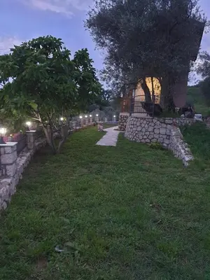 a walkway with a stone wall and a tree at Rustic Villas Barlovic in Ulcinj
