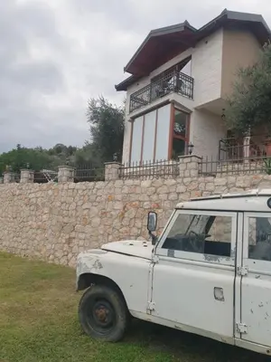 a white car parked in front of a stone wall at Rustic Villas Barlovic in Ulcinj