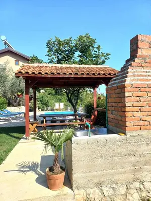 a wooden pergola with a picnic table in a yard at Rustic Villas Barlovic in Ulcinj