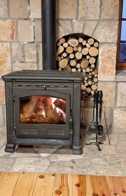a stone fireplace with a stove next to a pile of logs at Etno Villa Mokanji in Danilovgrad