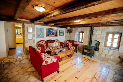 a living room with red furniture and a stone fireplace at Etno Villa Mokanji in Danilovgrad
