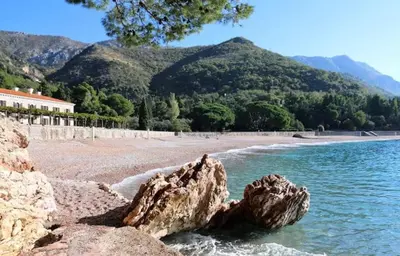 a rock in the water next to a beach at Beauty apartment in Blue star complex Pržno Montenegro in Pržno