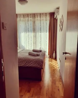 a bedroom with a bed and a window and a wooden floor at Beauty apartment in Blue star complex Pržno Montenegro in Pržno