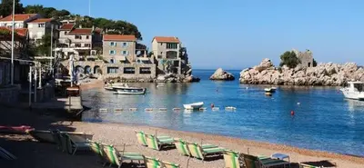a beach with chairs and boats in the water at Beauty apartment in Blue star complex Pržno Montenegro in Pržno