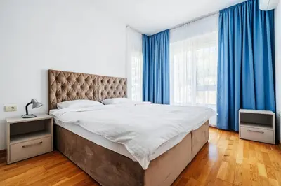 a bedroom with a large bed with blue curtains at Status-M Apartments 187 in Becici