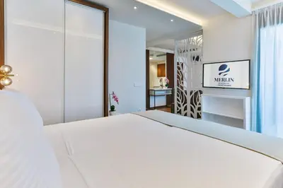 a bedroom with a white bed and a mirror at APARTMENTS MERLIN in Dobra Voda