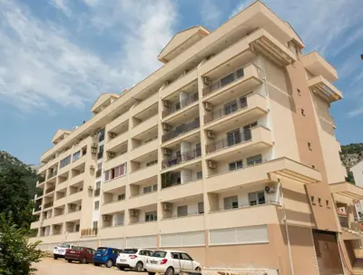 a large white building with cars parked in front of it at Mina Studio Apartment Budva in Budva