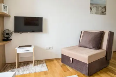 a living room with a chair and a flat screen tv at Mina Studio Apartment Budva in Budva
