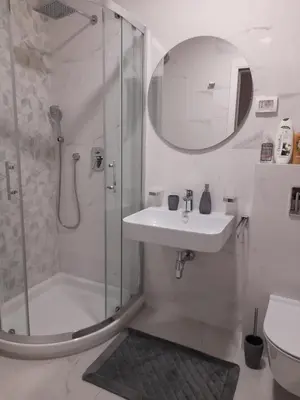 a white bathroom with a shower and a sink at Apartment Diamond in Podgorica