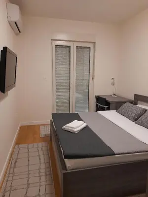a bedroom with a large bed with a tv on the wall at Apartment Diamond in Podgorica