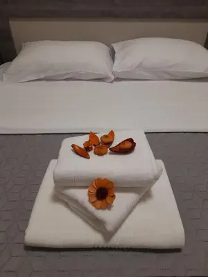 a bed with a white towel with a flower on it at Apartment Diamond in Podgorica