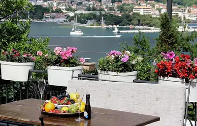 a table with a bowl of fruit and flowers on a balcony at Beautiful House Lara in Kotor