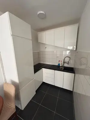 a kitchen with white cabinets and a black tile floor at Apartman Savo in Kotor