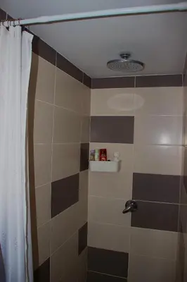 a bathroom with a shower with black and brown tiles at Apartman Livada Bar in Bar