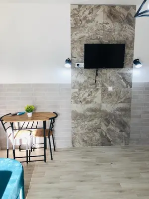 a room with a table and a tv on a stone wall at Margaritaville in Ulcinj