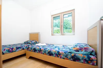 a bedroom with two beds and a window at Apartman DULY LUX in Pržno