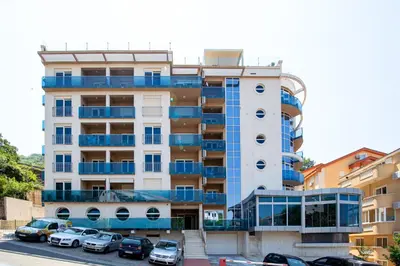 a tall building with cars parked in front of it at Apartman DULY LUX in Pržno