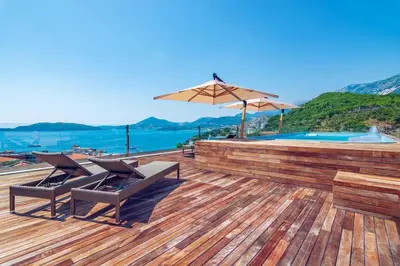 a wooden deck with a swimming pool and an umbrella at Apartman DULY LUX in Pržno
