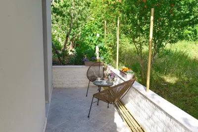 a patio with two chairs and a table on a porch at Verbalj apartment with swimming pool in Kotor