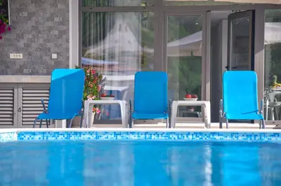 a swimming pool with two blue chairs next to a pool at Verbalj apartment with swimming pool in Kotor