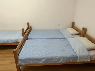 two beds in a room with blue sheets at Nikolić Apartmani in Bar