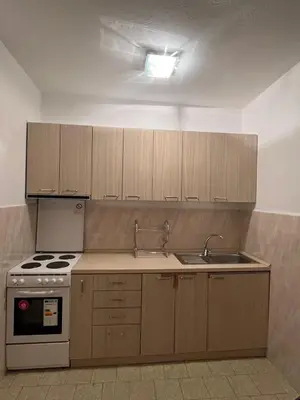 a kitchen with wooden cabinets and a stove and sink at Nikolić Apartmani in Bar