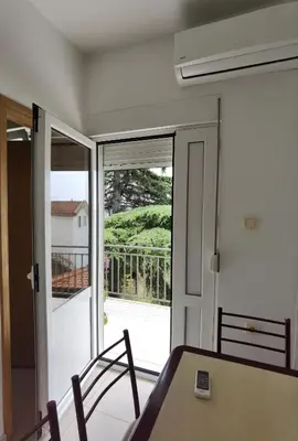 a dining room with a table and a sliding glass door at Nikolić Apartmani in Bar