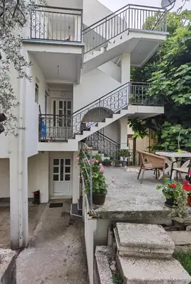 a white house with stairs and a patio at Nikolić Apartmani in Bar