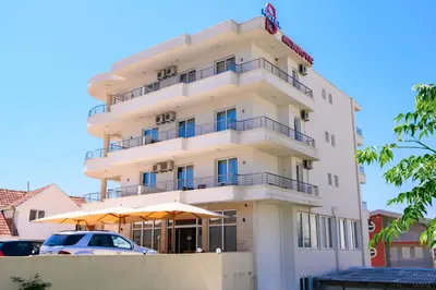 a tall white building with umbrellas in front of it at MS Hotel in Dobra Voda
