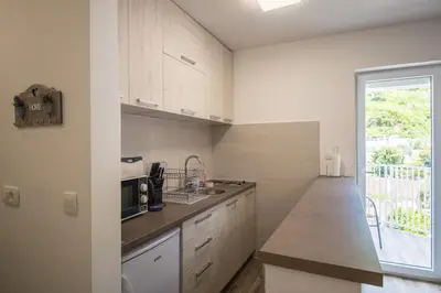 a kitchen with white cabinets and a large window at Studio Apartment Urke in Budva