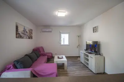 a living room with a purple couch and a tv at Studio Apartment Urke in Budva