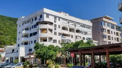 a large white building with cars parked in front of it at Studio Apartment Urke in Budva