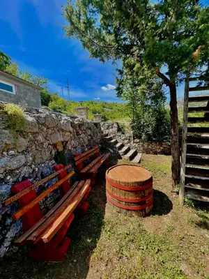 a group of benches sitting next to a stone wall at Vikendica,Bungalovi Lipska pećina in Cetinje
