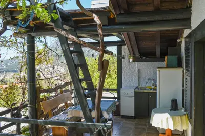 a kitchen with a ladder and a table and a refrigerator at Guest House Scepanovic in Sutomore