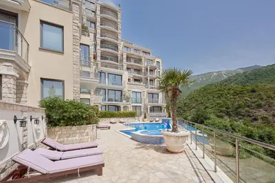 a building with a palm tree and a swimming pool at BigMontenegro Dreams in Becici