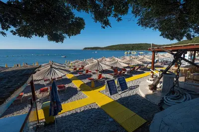 a beach with chairs and umbrellas and the ocean at Dubrave apartmani in Budva
