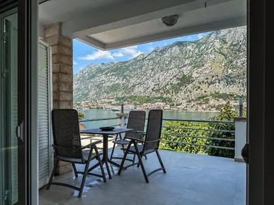 a balcony with a table and chairs and a mountain at ChillOut apartment in Kotor Bay in Kotor