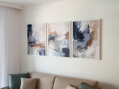 three paintings on a white wall above a couch at ChillOut apartment in Kotor Bay in Kotor