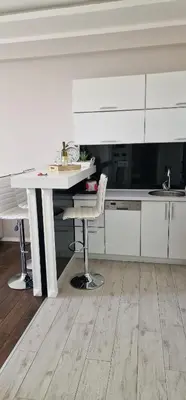 a white kitchen with a table and a chair at Luxury apartment in Victoria Palace Budva center in Budva
