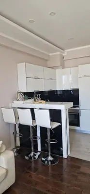 a kitchen with white cabinets and a counter with bar stools at Luxury apartment in Victoria Palace Budva center in Budva