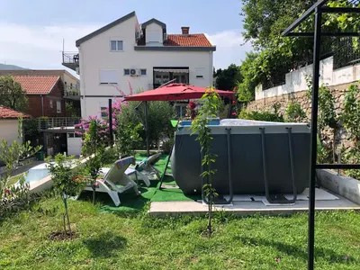 a garden with a hot tub and an umbrella at Vila Marina in Sutomore