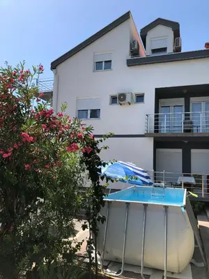 a building with a swimming pool and an umbrella at Vila Marina in Sutomore