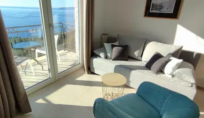 a living room with a couch and a view of the ocean at Almond Apartments in Sveti Stefan